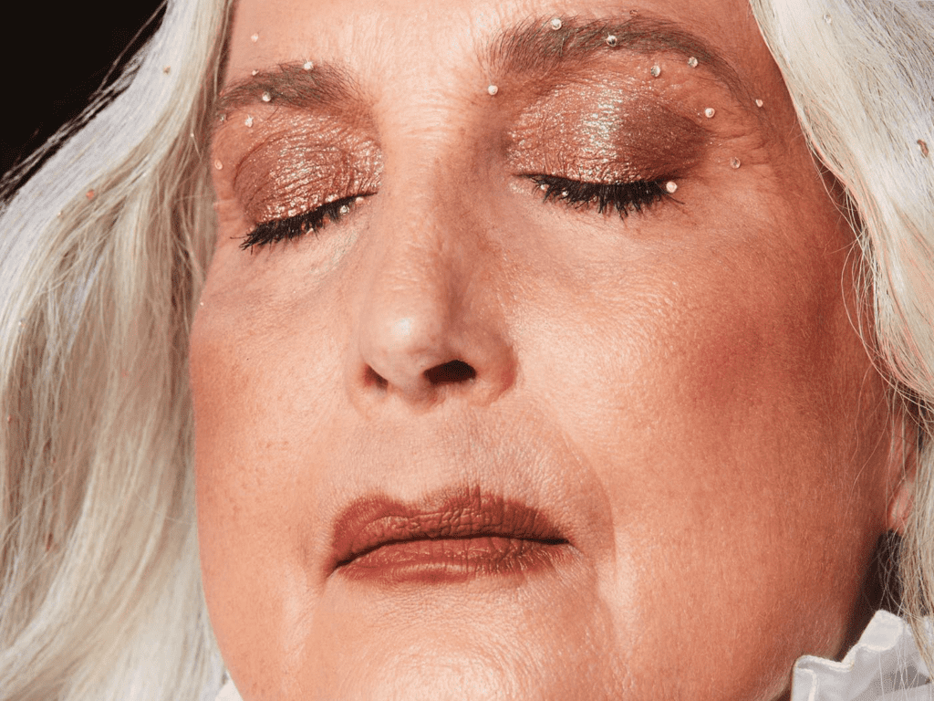 A view of an older lady with closed eyes and shimmery eye makeup on