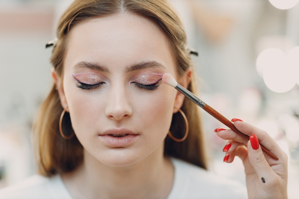 Beautiful Young Woman Applying eyeshadow with brush