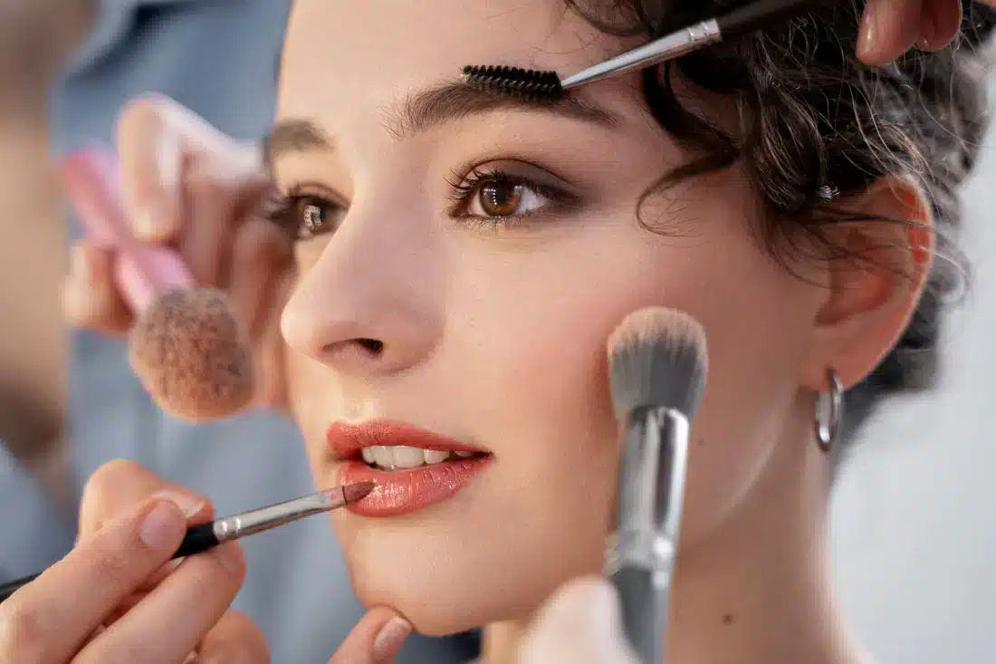 close up of a bride with several brushes on her face for wedding makeup