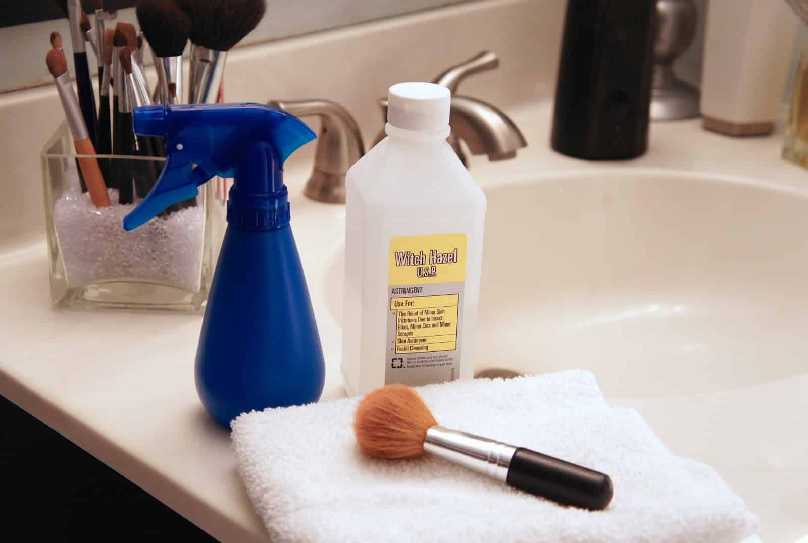 makeup bruhses with a towel on bathroom sink a spray bottle