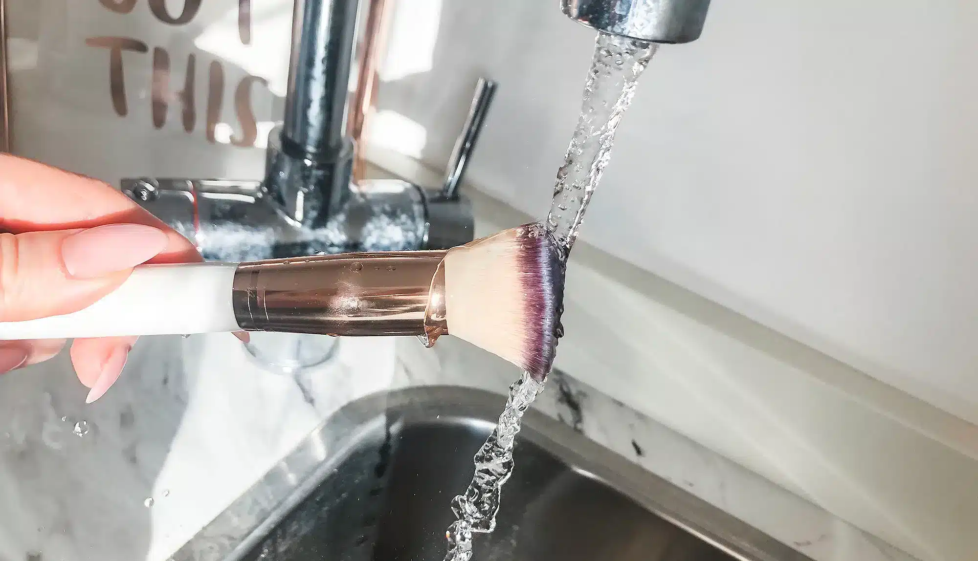 makeup brush being washed in tap water