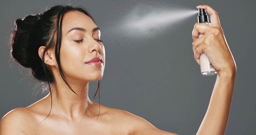 woman and spray after makeup studio with product for mockup in cosmetics on gray background.