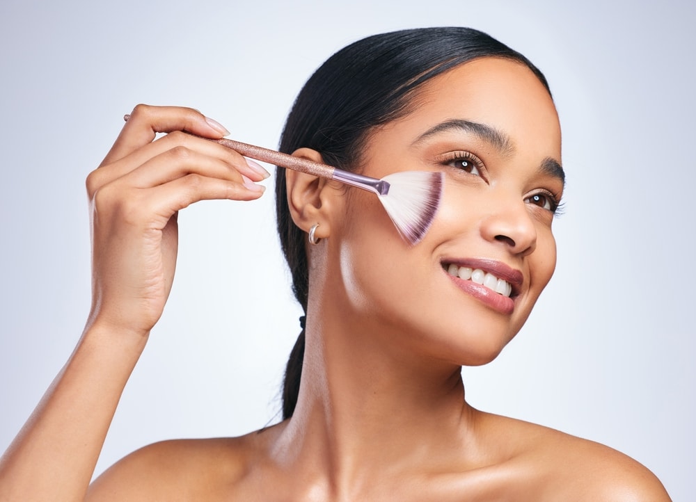 woman applying highlighter with a brush