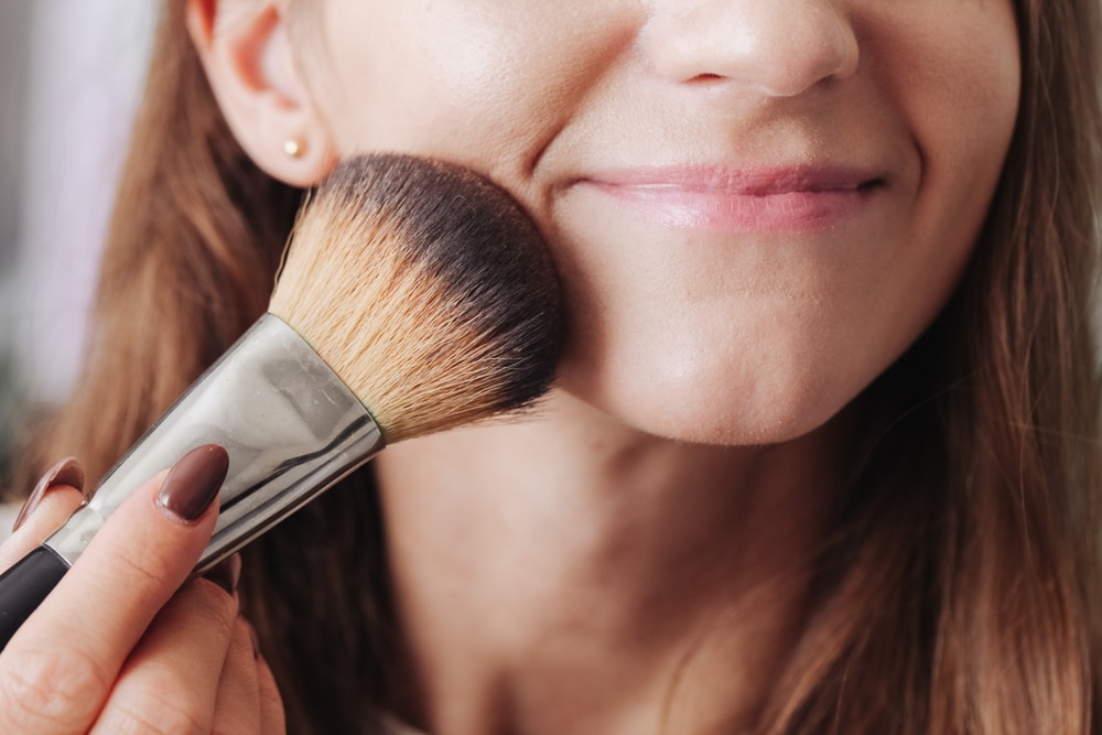 zoomed view of a woman applying blush on with a brush