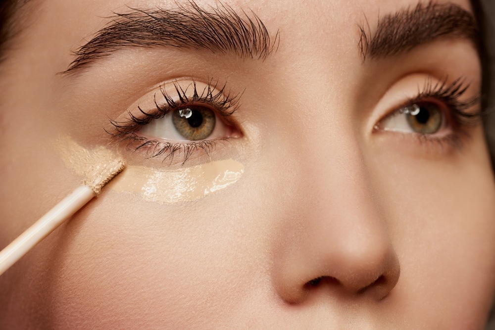 Young female model applying under eye concealer.