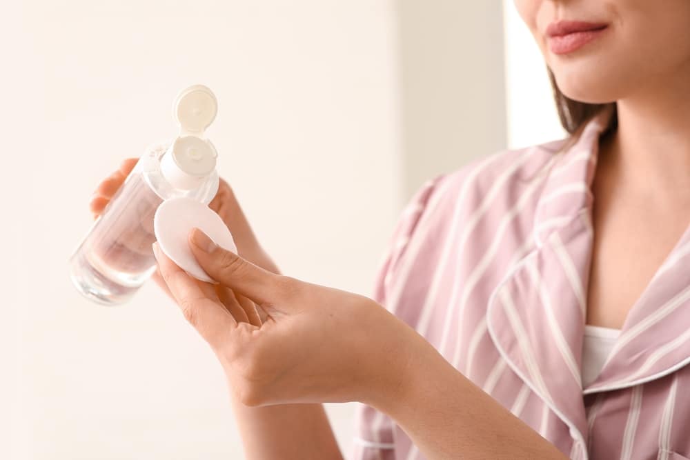 Young Woman In Pajamas With Cotton Pad And Micellar Water