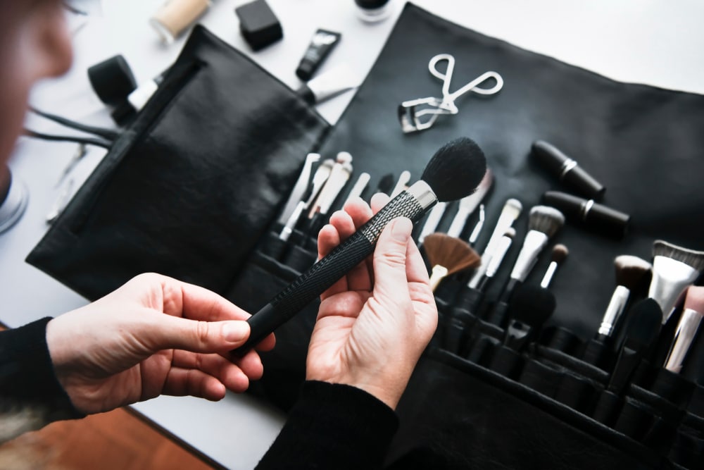 A lot of make up brushes with metal details placed on the table in brush roll.