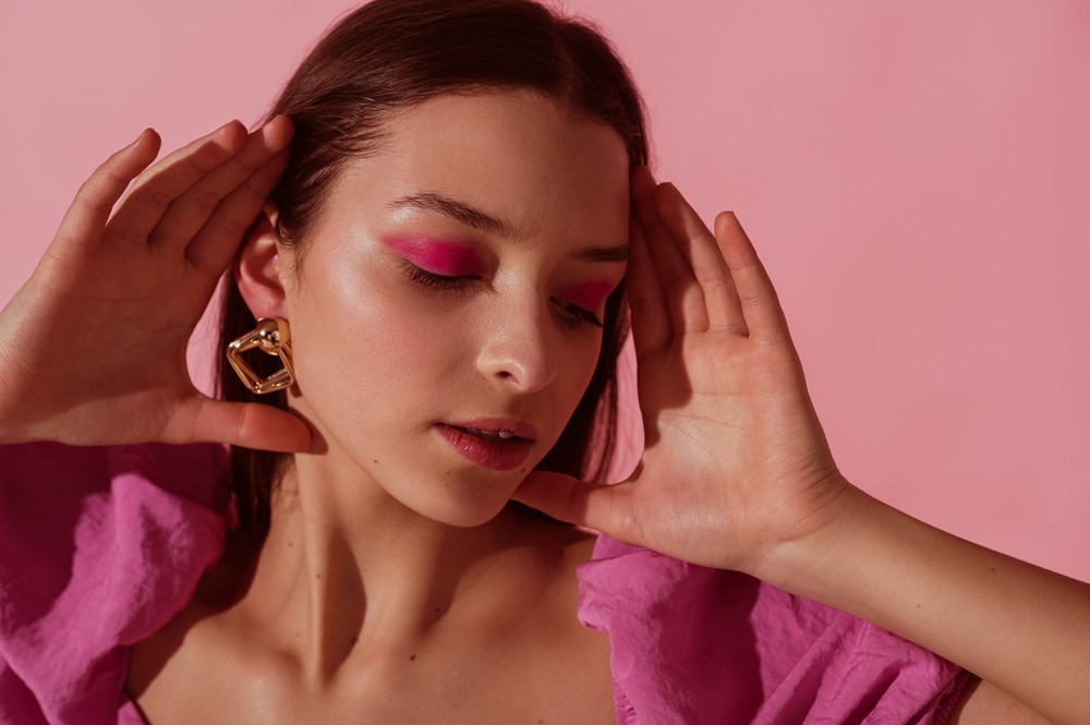 A view of a woman wearing hot pink bold makeup